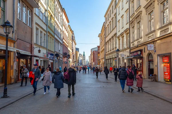 Krakow, Poland - 14 March, 2022: Tourists walking through Florianska street with St. Mary's Basilica church in background