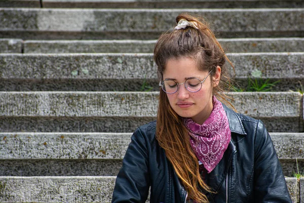 Taş merdivenlerde deri ceketli bir kadın.