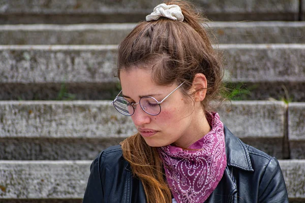 Taş merdivenlerde deri ceketli bir kadın.