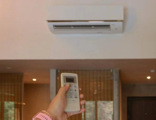 hand holding air conditioner remote control in domestic room
