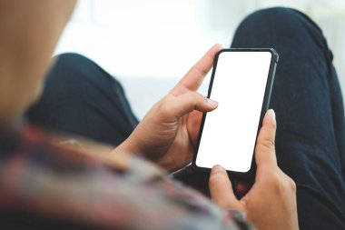 Kanepede oturup akıllı telefon kullanan sıradan bir adam. Metin iletiniz veya bilgi içeriğiniz için boş ekran.