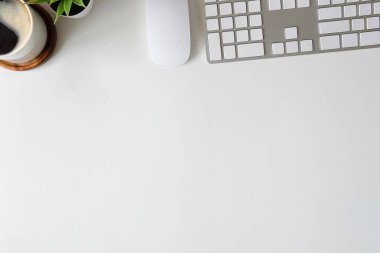 Klavyesi, kahve fincanı ve çiçekli beyaz ofis masası..