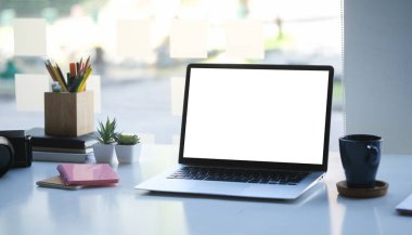 Modern ofisteki beyaz masaya boş ekran ve kahve fincanı ile bilgisayar laptopunu taklit et.