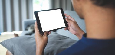 Oturma odasında otururken elinde boş ekranlı akıllı bir telefon tutan adam..