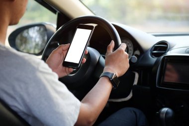 Kesilmiş görüntü. Şoför araba kullanırken telefonu kullanıyor. Yuvarlak kenarlı modern akıllı telefon. Model için izole ekran. Arka planda araba navigasyon görüntüsü.