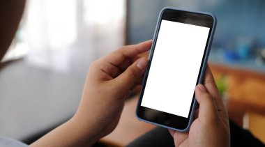 Casual woman sitting on couch and using smart phone. Blank screen for your text message or information content.	