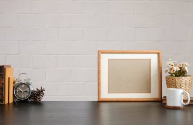 Ev bitkisi, kamera ve kahve fincanı ile beyaz masa ve tuğla duvarlı şık çalışma alanı.