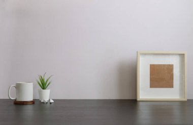 Ev bitkisi, kamera ve kahve fincanı ile beyaz masa ve tuğla duvarlı şık çalışma alanı.