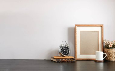 Ev bitkisi, kamera ve kahve fincanı ile beyaz masa ve tuğla duvarlı şık çalışma alanı.