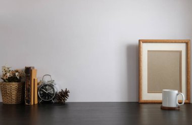 Ev bitkisi, kamera ve kahve fincanı ile beyaz masa ve tuğla duvarlı şık çalışma alanı.