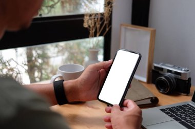 Close up view of businessman holding mock up smart phone with blank screen.	