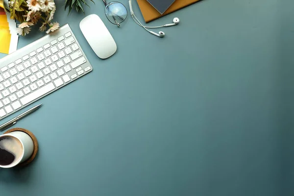 Kahve fincanı, kitap, kulaklık ve klavyeli yaratıcı çalışma alanı.