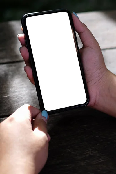 Woman Holding Mock Smart Phone Empty Screen Wooden Table — Stockfoto