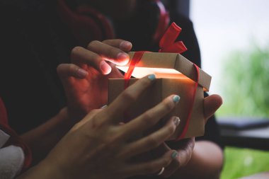 Parlayan Noel hediye kutusunu açan adam.