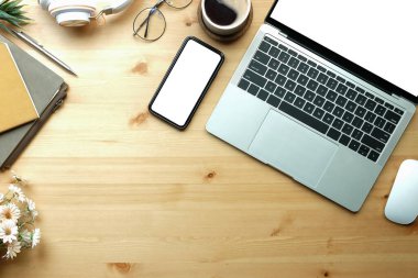 Yukarıda dizüstü bilgisayar, akıllı telefon, kahve fincanı ve defter var..