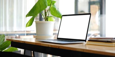 Close up computer laptop with white screen on wood table in modern office.	
