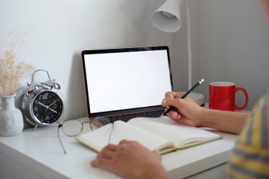 Bilgisayarla çalışan ve not defterine notlar alan görüntüleme öğrencisini kapat.