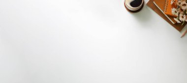 Üst düzey kahve fincanı, ev bitkisi ve beyaz masadaki boş defter. Boşluğu kopyala.