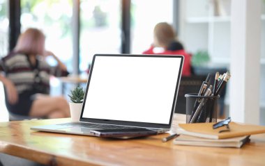 Laptop computer, books and office supplies on wooden table.