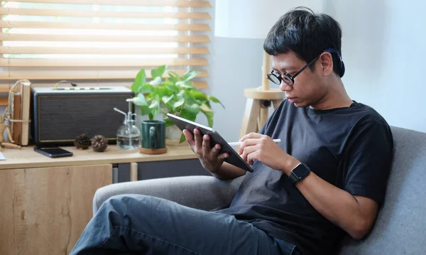 소파에 앉아서 디지털 태블릿으로 일하는 청년을 가르치는 — 스톡 사진