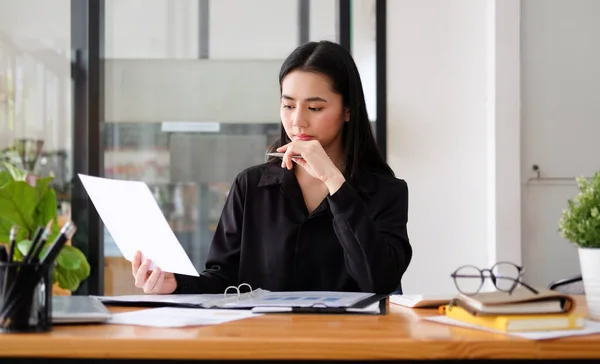 職場に座って財務書類を読む若いアジアのビジネス女性 — ストック写真