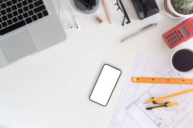 Engineering and architecture workspace with smart phone, laptop, blueprints, measurement and portable radio transceiver.