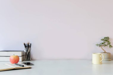 Minimal workplace with bonsai, coffee cup and pencil holder on white table. Copy space for your advertising text.