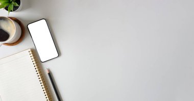 Top view mockup smart phone, notebook, coffee cup and cactus on white table. Blank screen for your advertising text.