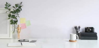 Kamera, kitap, kahve fincanı, resim ve çiçekli yaratıcı tasarım işyeri.