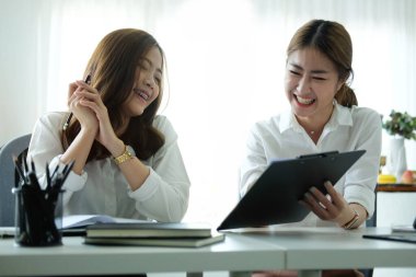 Modern ofiste birlikte çalışan iki neşeli iş kadını..