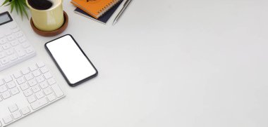 Akıllı telefon, hesap makinesi, kahve fincanı ve defterin beyaz masadaki görüntüsü..