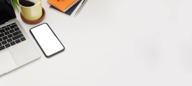 Akıllı telefon, dizüstü bilgisayar, defter ve kahve fincanı olan ofis masası. Boşluğu kopyala.