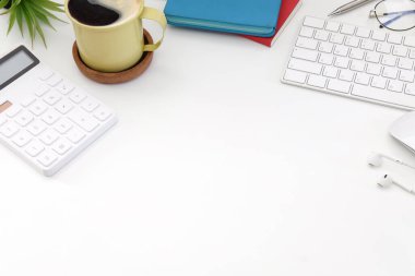 Üst görünüm hesap makinesi, kahve fincanı, kablosuz klavye ve kulaklıklar beyaz ofis masasında..