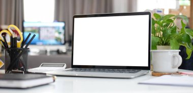 Bilgisayar laptopu, kahve fincanı ve kalem tutacağı beyaz masada..