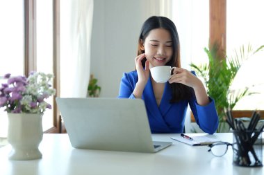 İş yerinde oturan ve kahve içen çekici bir iş kadını..