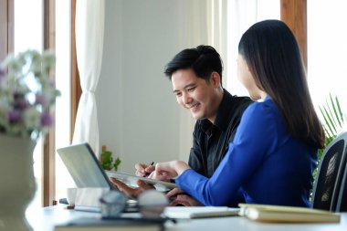 İki gülümseyen iş arkadaşı birlikte yeni bir proje üzerinde çalışıyor..