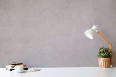 Lambalı, çiçekli, kitaplı ve beyaz arka planda kahve fincanlı yaratıcı bir iş yeri. Boşluğu kopyala.