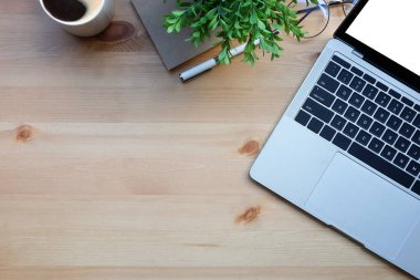 Üst görünüm dizüstü bilgisayar, kitaplar, saksı bitkisi ve kahve fincanı ahşap masada..