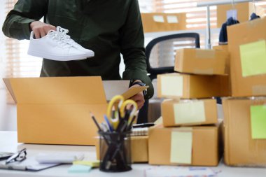 Kırpılmış küçük işletme sahibi müşteriye teslimat için karton kutuda ürün paketliyor..