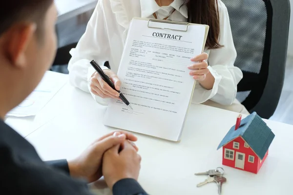 Genç Asyalı adam emlakçılarla ofiste ev kiralama ya da satın alma konusunda görüşüyor..