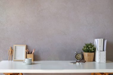 Kitapları, resim çerçevesi, ev bitkisi ve kahve fincanı olan şık bir iş yeri..