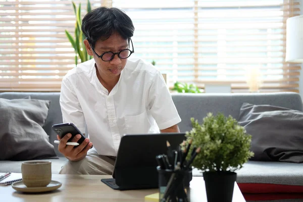 Asian Male Freelancer Working Home Laptop Using Smart Phone — Stock Photo, Image