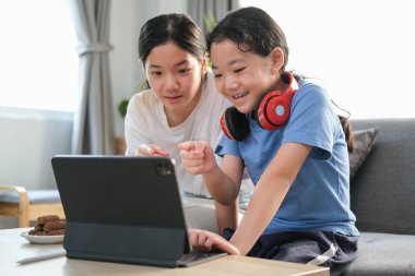 İki sevimli kız kardeş online oyun oynuyor ya da evde dijital tabletle video izliyorlar..