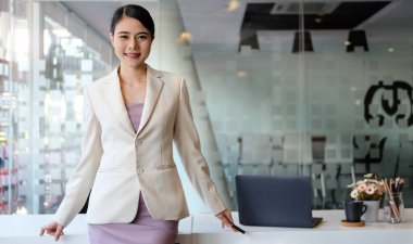 Modern işyerindeki muhteşem iş kadını kameraya gülümsüyor..