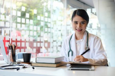 Hasta dosyasını tutan ve kameraya gülümseyen kendine güvenen bir kadın doktor. Tıp ve sağlık hizmetleri kavramı.