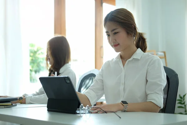 オフィスで彼女の同僚と座っている間 コンピュータのラップトップを使用して魅力的なアジアの女性のオフィスワーカー — ストック写真