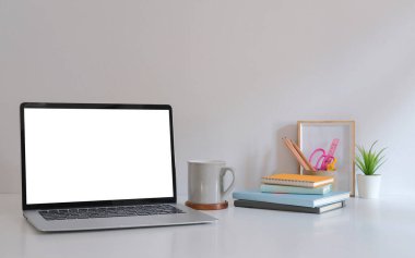 Boş ekran, kahve fincanı, kitap ve resim çerçeveli bir model dizüstü bilgisayar..
