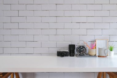 Kamera, kahve fincanı, çerçeve, saksı ve kırtasiye malzemesi olan yaratıcı bir iş yeri..