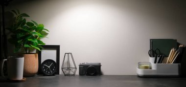 Kırtasiye malzemesi, resim çerçevesi ve siyah masa üzerinde saksı bitkisi olan şık bir iş yeri. Grafik görüntüleme kurgusu için alanı kopyala.