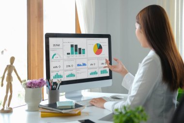 Arka plan iş kadını modern işyerindeki bilgisayarda finansal grafiği analiz ediyor.